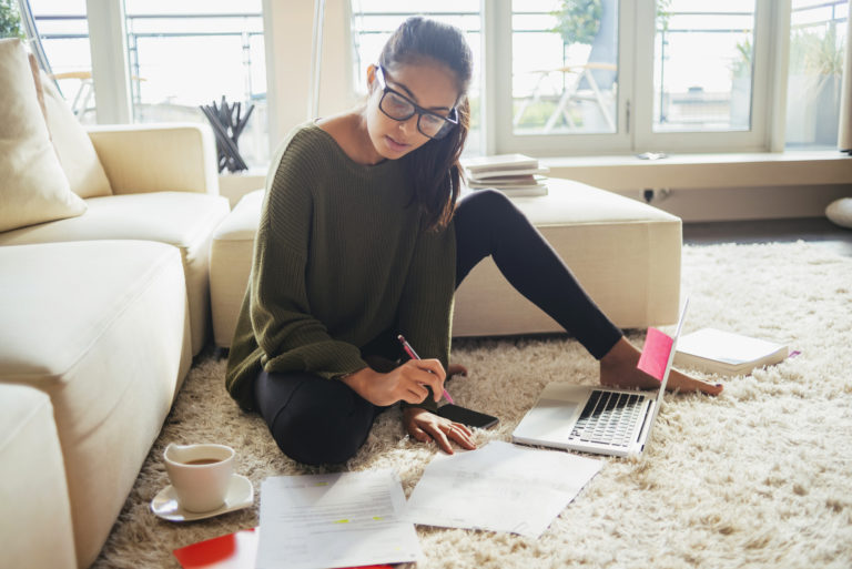 young woman studying in her living room,sitting on the carpet